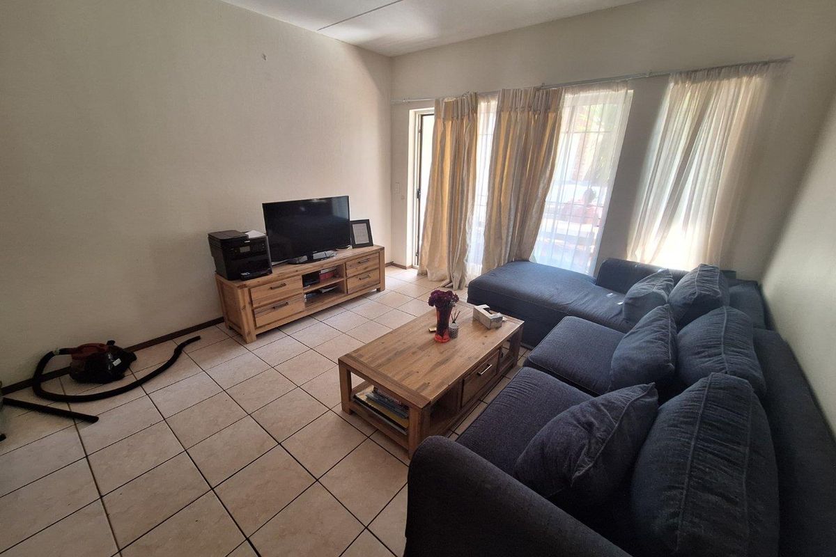 A living room featuring tiled flooring and a sliding glass door providing access to the outdoor area.