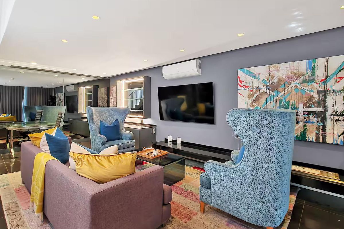 Modern living room featuring recessed downlights, split-system air conditioning, built-in cabinetry, and mirrored wall accents with polished tiled flooring.