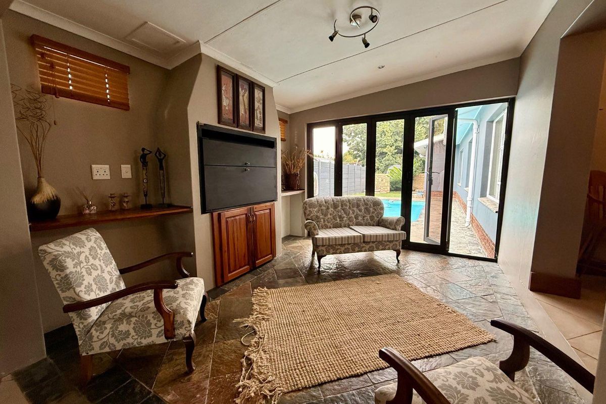 A cozy living room featuring slate tile flooring, a built-in fireplace, and large folding glass doors that open directly to the pool area.