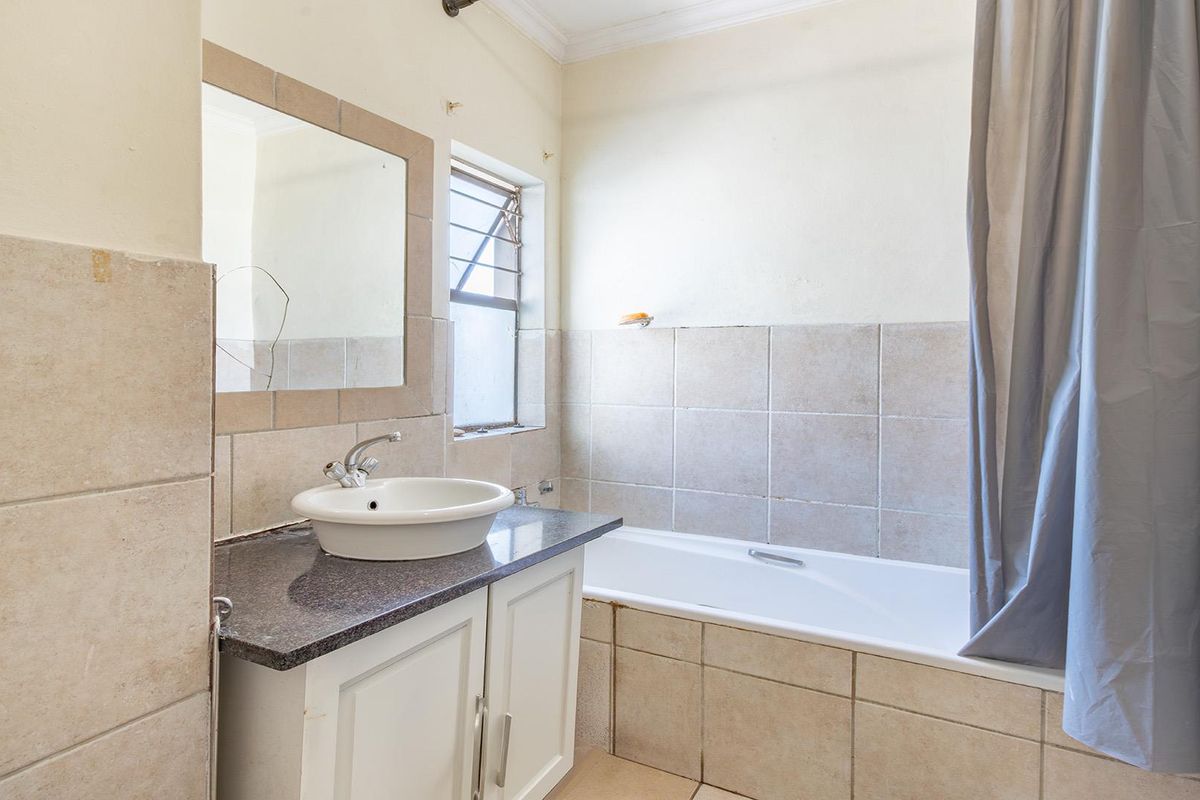 A functional bathroom featuring a vanity with a vessel sink, granite countertop, and a tiled bathtub surround with a shower curtain.