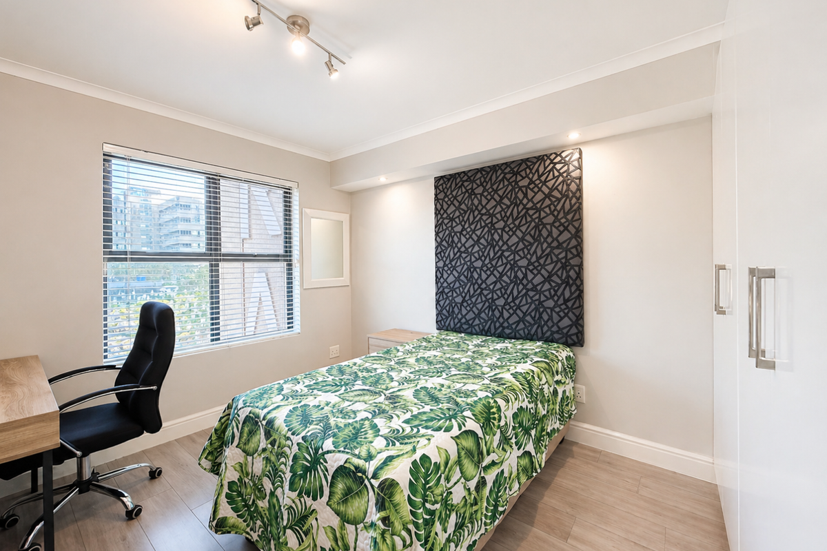 A well-maintained bedroom featuring laminate flooring, built-in wardrobes, track lighting, and a window with venetian blinds.