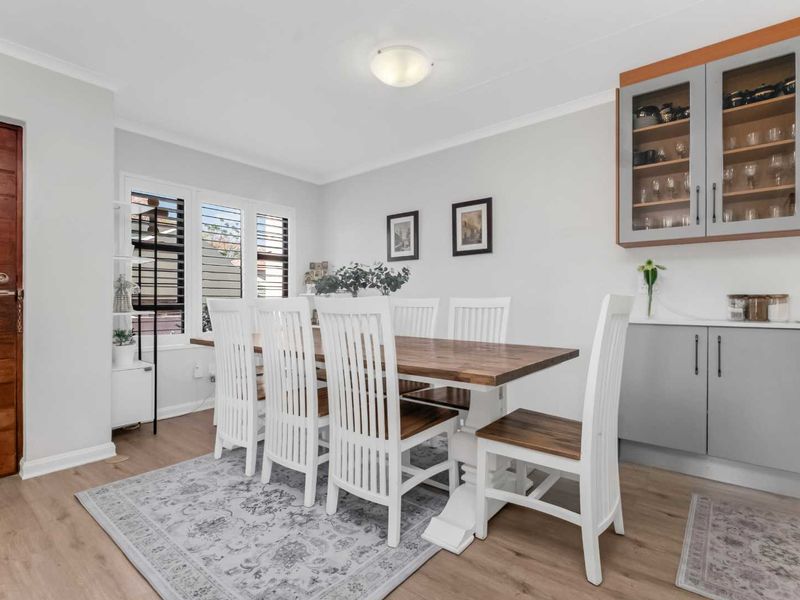 A bright dining room featuring laminate flooring, built-in cabinetry, and shutter blinds, providing a functional and well-maintained space for family meals.