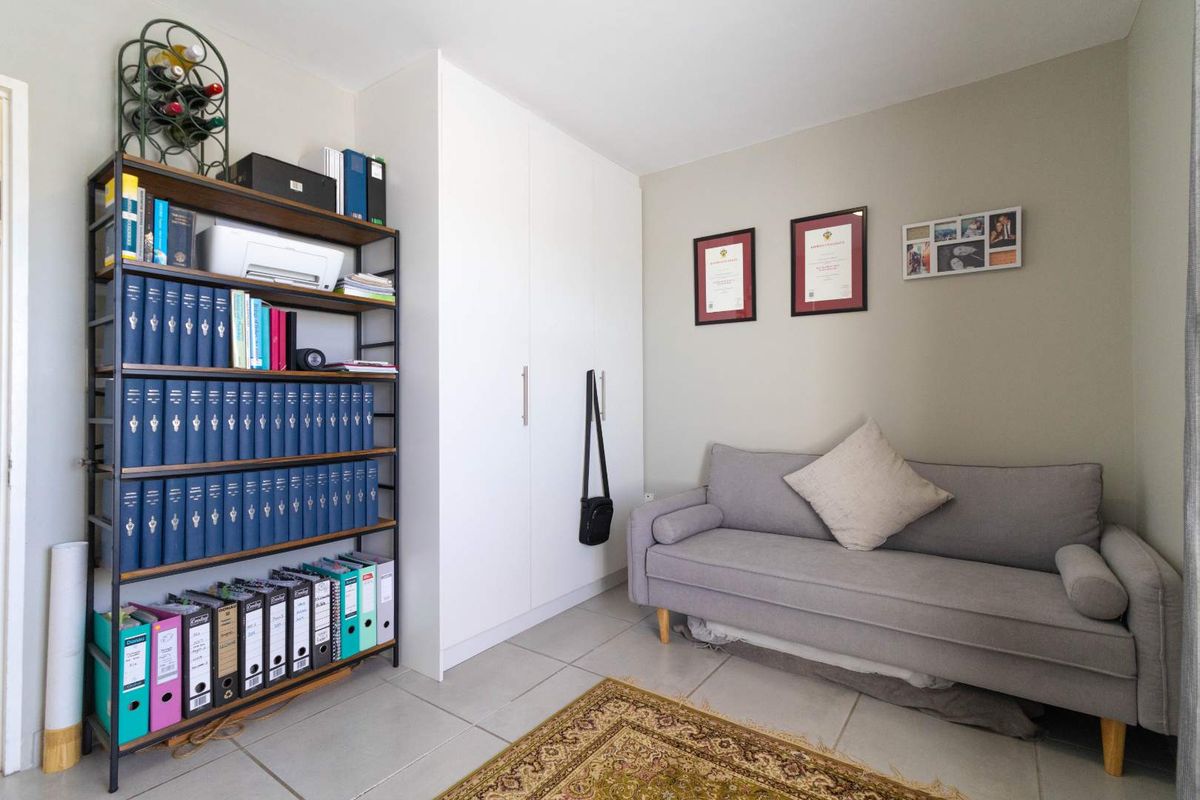 A functional bedroom featuring built-in floor-to-ceiling cabinetry and neutral tiled flooring, offering versatile space for storage or a home office setup.