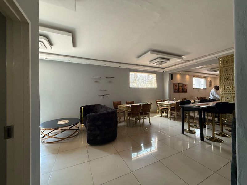 Spacious open-plan retail or dining area featuring tiled flooring, decorative ceiling bulkheads with recessed lighting, and secure window treatments.