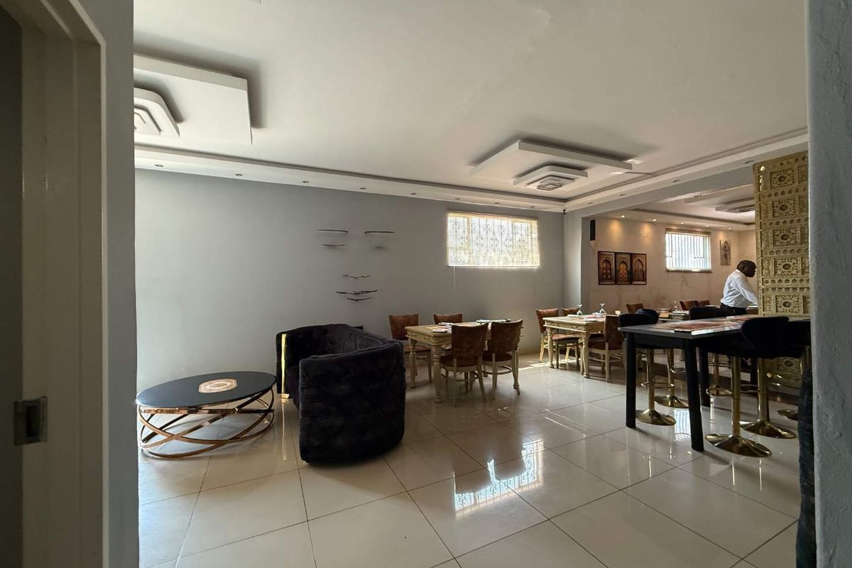 Spacious open-plan retail or dining area featuring tiled flooring, decorative ceiling bulkheads with recessed lighting, and secure window treatments.