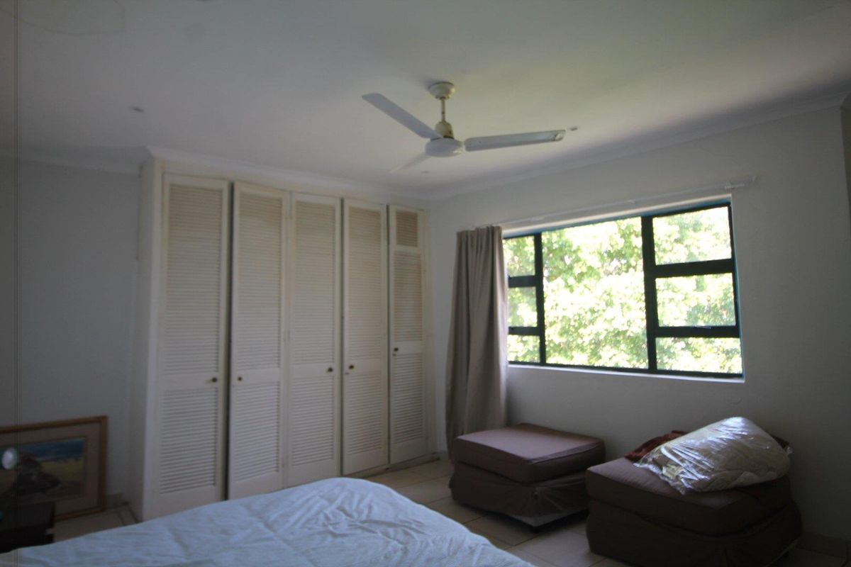 A bedroom featuring built-in louvered door cupboards and a ceiling fan, providing functional storage and ventilation.