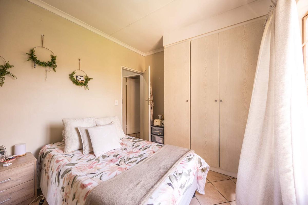 A bedroom featuring built-in cupboards and tiled flooring, offering a functional space with neutral wall tones.