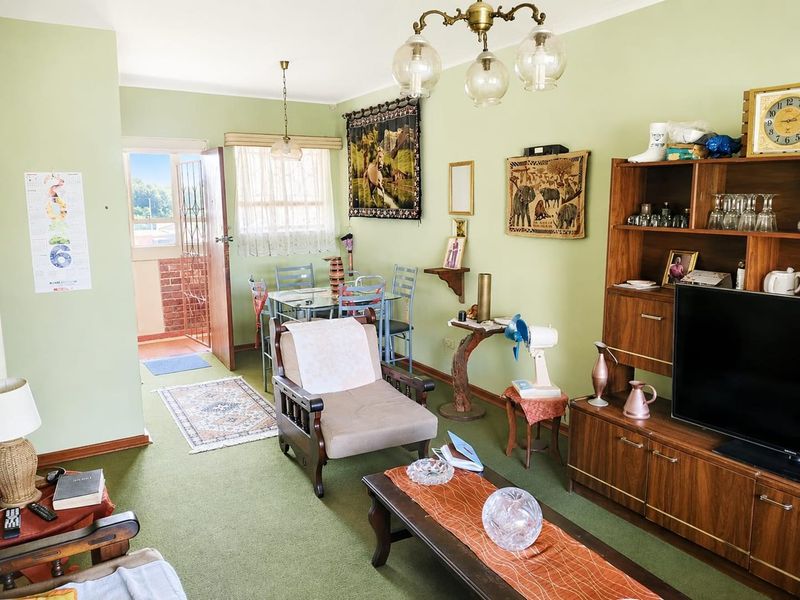 Open plan living and dining area featuring green carpeting, coving, and direct access to an outdoor balcony through a security gate.