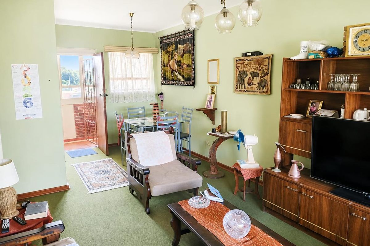 Open plan living and dining area featuring green carpeting, coving, and direct access to an outdoor balcony through a security gate.