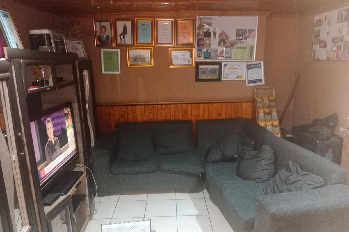 A living room featuring wooden ceiling and wall paneling with ceramic floor tiles, offering a dated aesthetic that could benefit from modern updates.