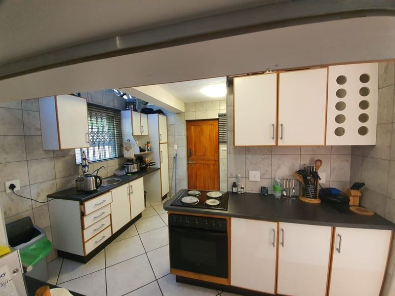 Functional kitchen featuring white cabinetry, dark laminate countertops, built-in oven and hob, tiled backsplash, and tiled flooring.
