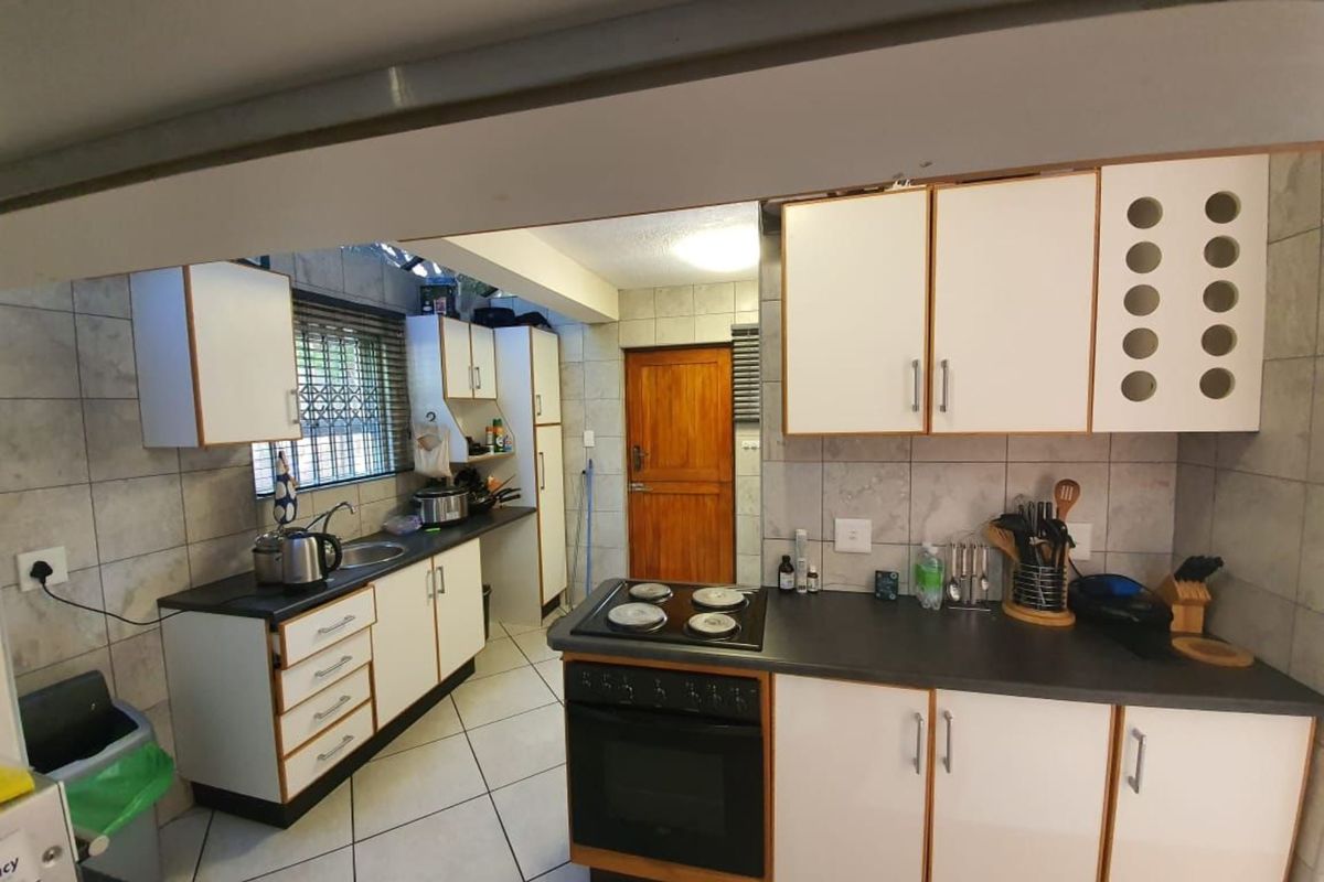 Functional kitchen featuring white cabinetry, dark laminate countertops, built-in oven and hob, tiled backsplash, and tiled flooring.