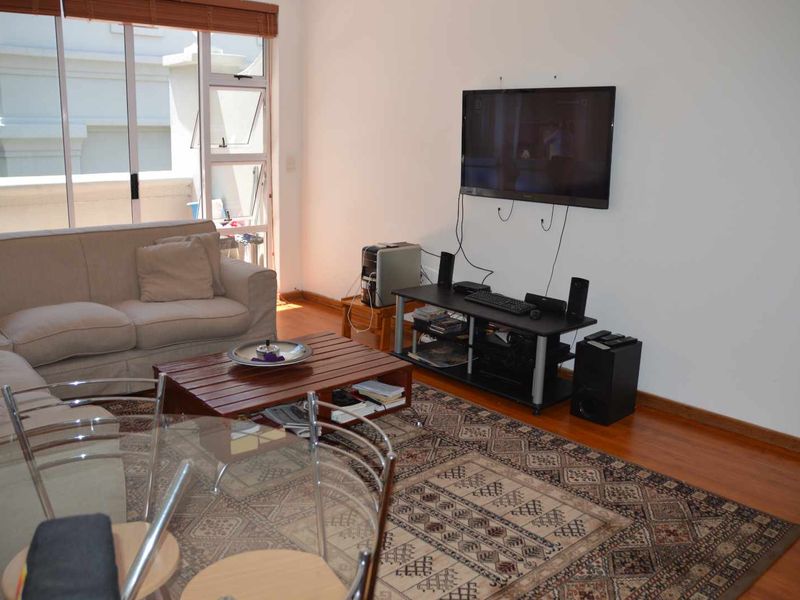 A living room featuring timber flooring and large sliding glass doors that provide access to an outdoor area.