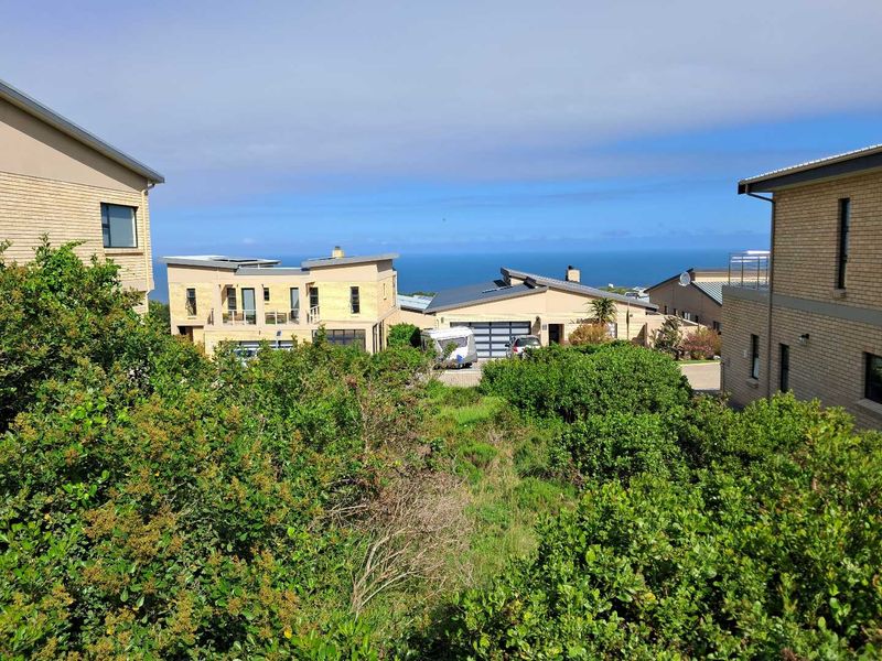 A scenic elevated view overlooking the surrounding residential estate with a clear horizon line and ocean backdrop.