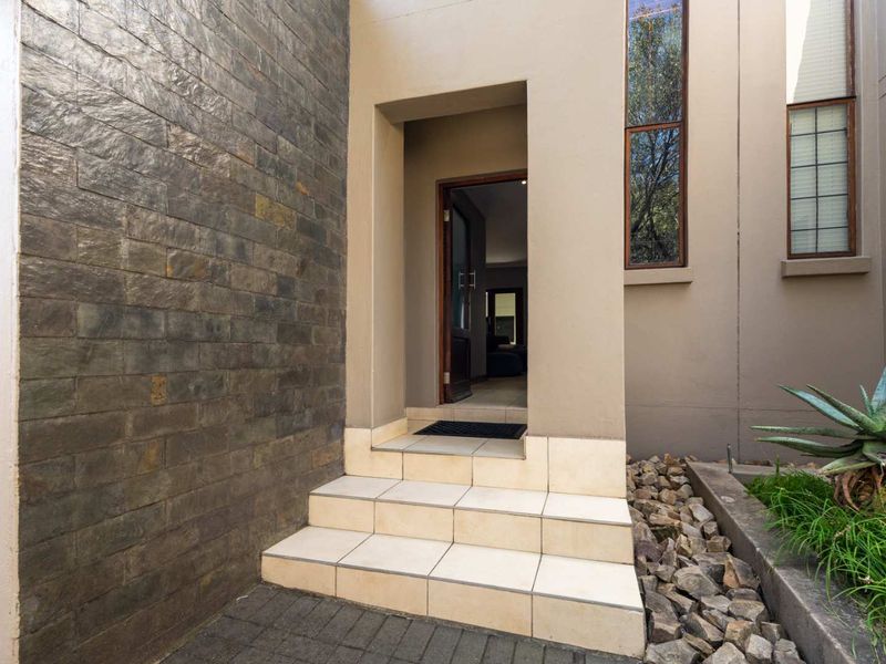 A modern townhouse entrance featuring stone cladding, tiled steps, and tall windows, creating a welcoming and contemporary facade.
