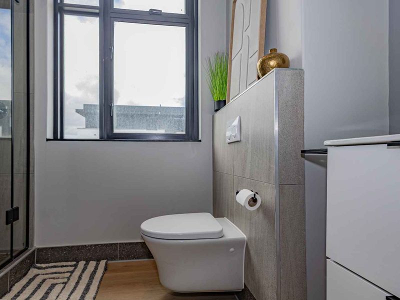 Modern bathroom featuring a wall-hung toilet with a concealed cistern, tiled feature wall, and a glass-enclosed shower.