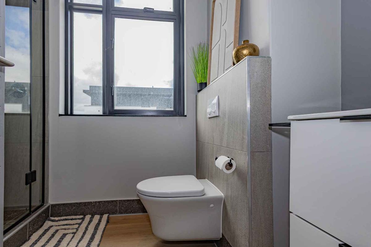 Modern bathroom featuring a wall-hung toilet with a concealed cistern, tiled feature wall, and a glass-enclosed shower.
