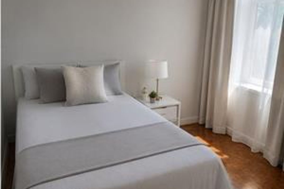 A bright and well-maintained bedroom featuring hardwood flooring and neutral wall finishes, offering a clean and comfortable living space.