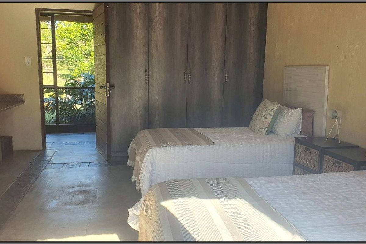 A bedroom featuring built-in cupboards, polished concrete flooring, and a built-in vanity area with direct access to an outdoor patio.