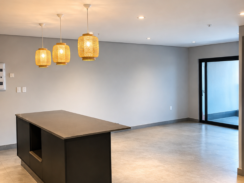 A spacious open-plan living area featuring a modern kitchen island with stone countertop, neutral tiled flooring, and access to an outdoor balcony.