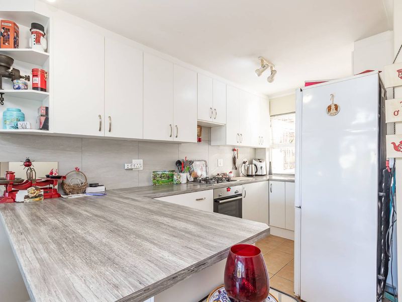 A functional kitchen featuring white cabinetry, wood-look laminate countertops, a gas hob, and a built-in oven with tiled backsplash and flooring.