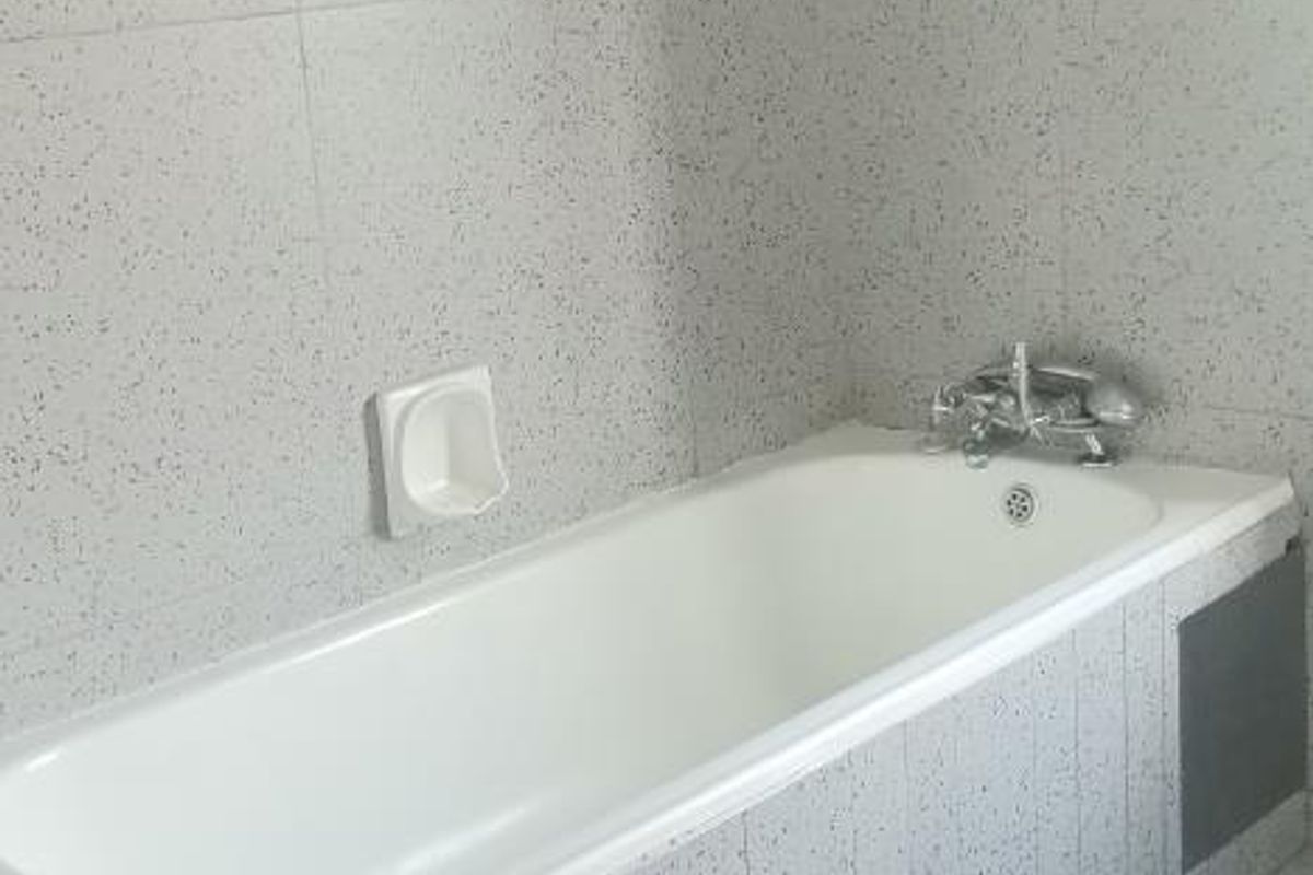 A clean, functional bathroom featuring a standard bathtub with tiled surround and matching floor tiles.