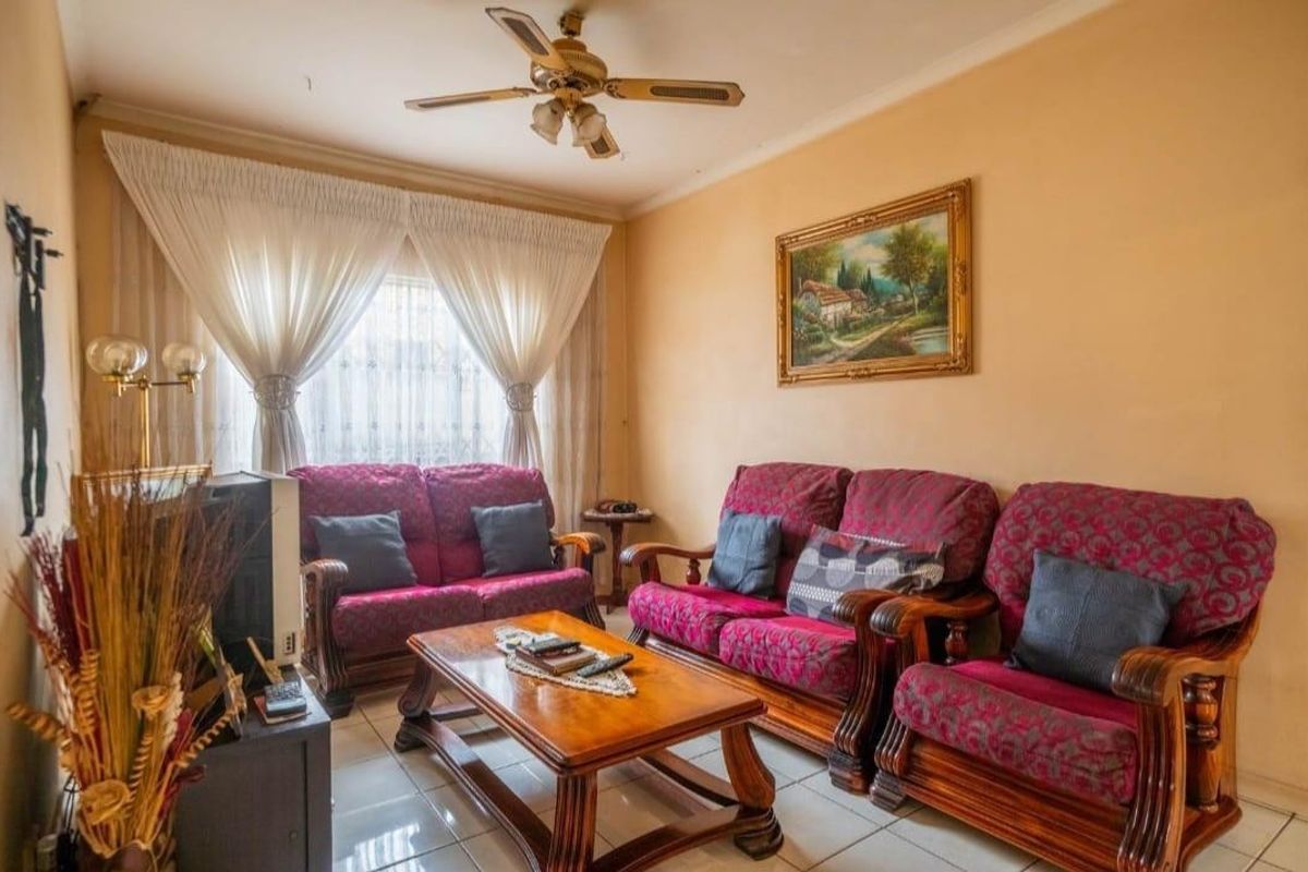 A comfortable living room featuring tiled flooring, a ceiling fan, and coved cornicing, providing a functional and well-maintained space for relaxation.