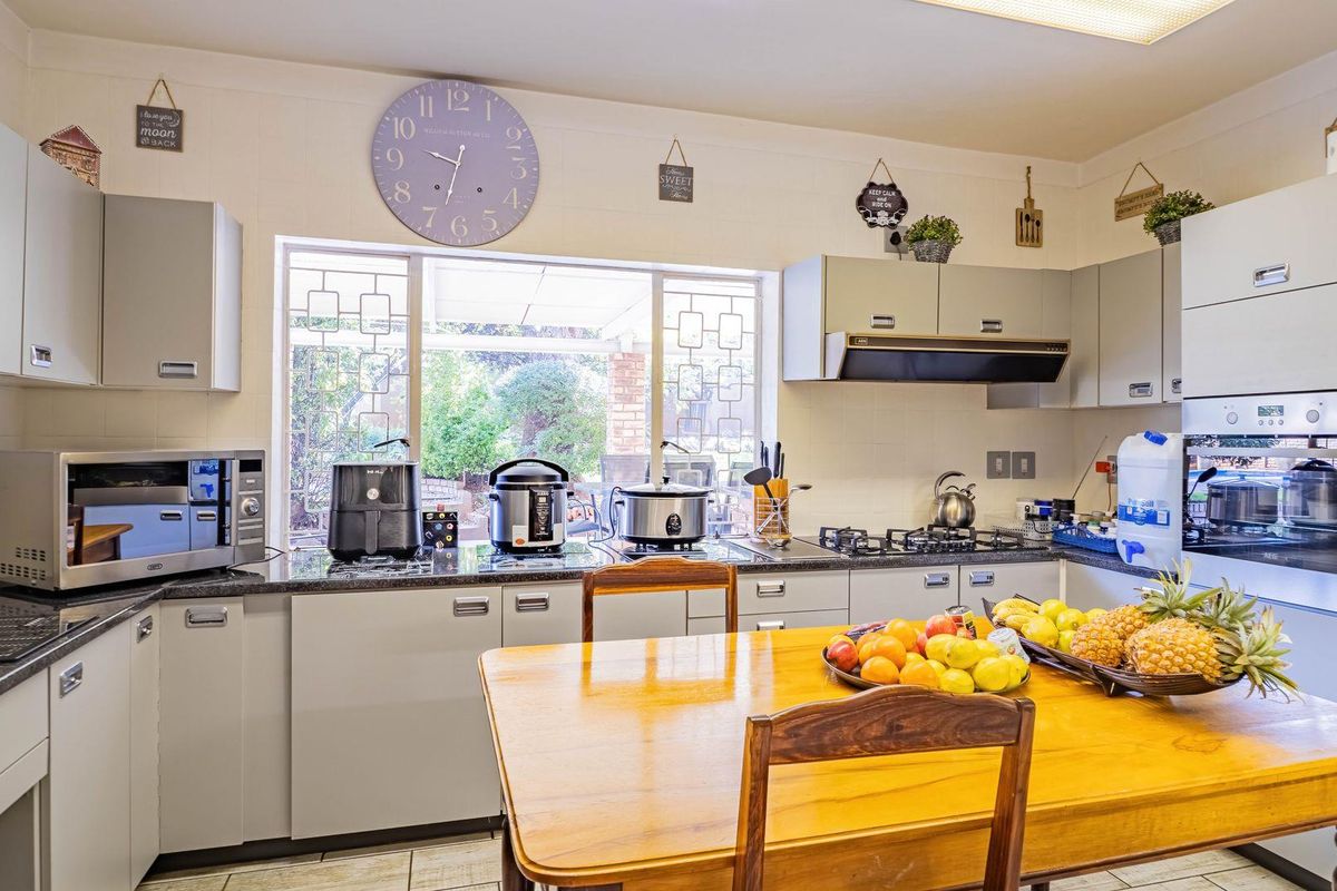 A functional kitchen featuring built-in cabinetry, a gas hob, an integrated oven, and an extractor fan, with a window overlooking the rear garden.