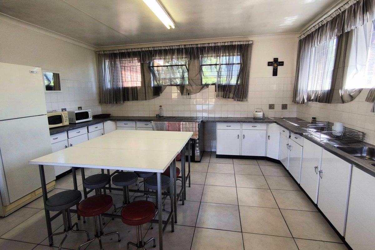 Functional kitchen featuring extensive built-in cabinetry, laminate countertops, double stainless steel sink, and tiled backsplash with ceramic flooring.