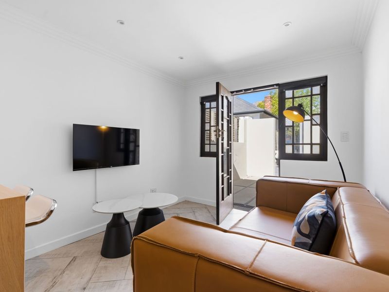 A bright living room featuring herringbone tile flooring, recessed downlights, and direct access to an outdoor area through classic french doors.