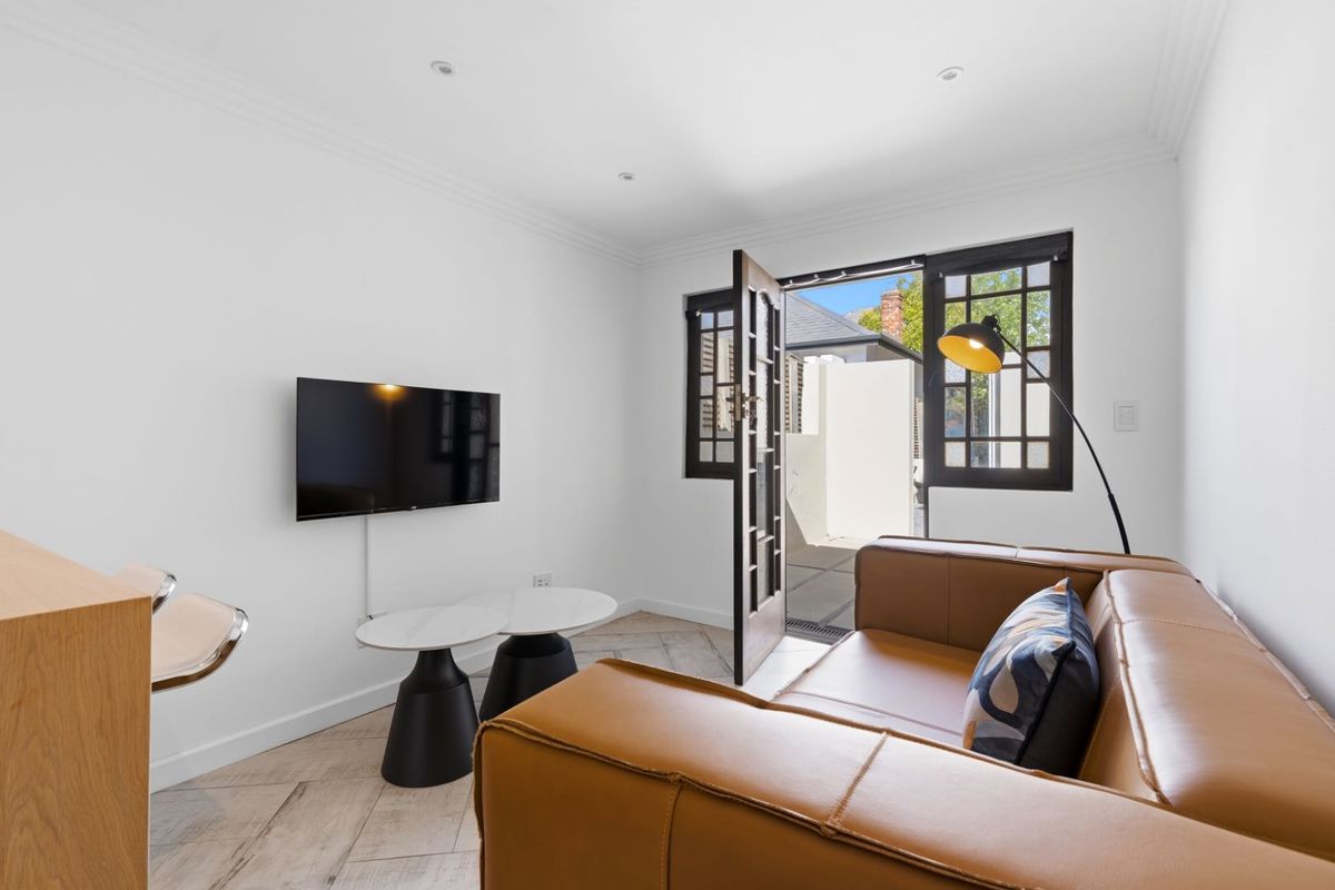 A bright living room featuring herringbone tile flooring, recessed downlights, and direct access to an outdoor area through classic french doors.