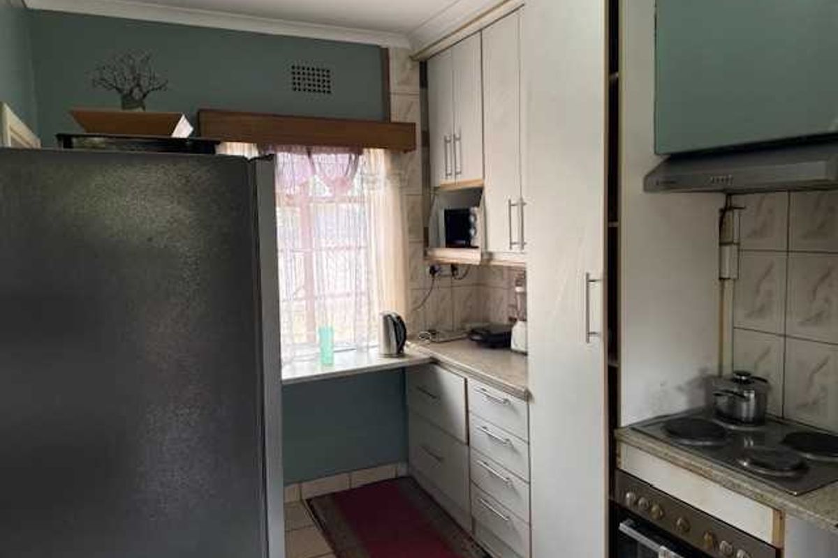A functional kitchen featuring built-in cabinetry, a stove with extractor fan, and a small breakfast nook area by the window.
