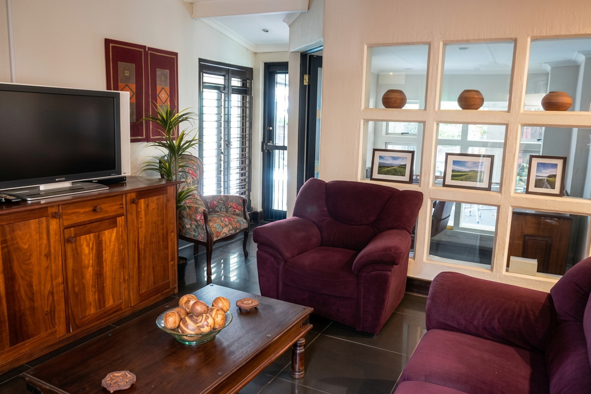 A living room featuring dark tiled flooring, a built-in decorative room divider with glass panels, and access to an exterior door.