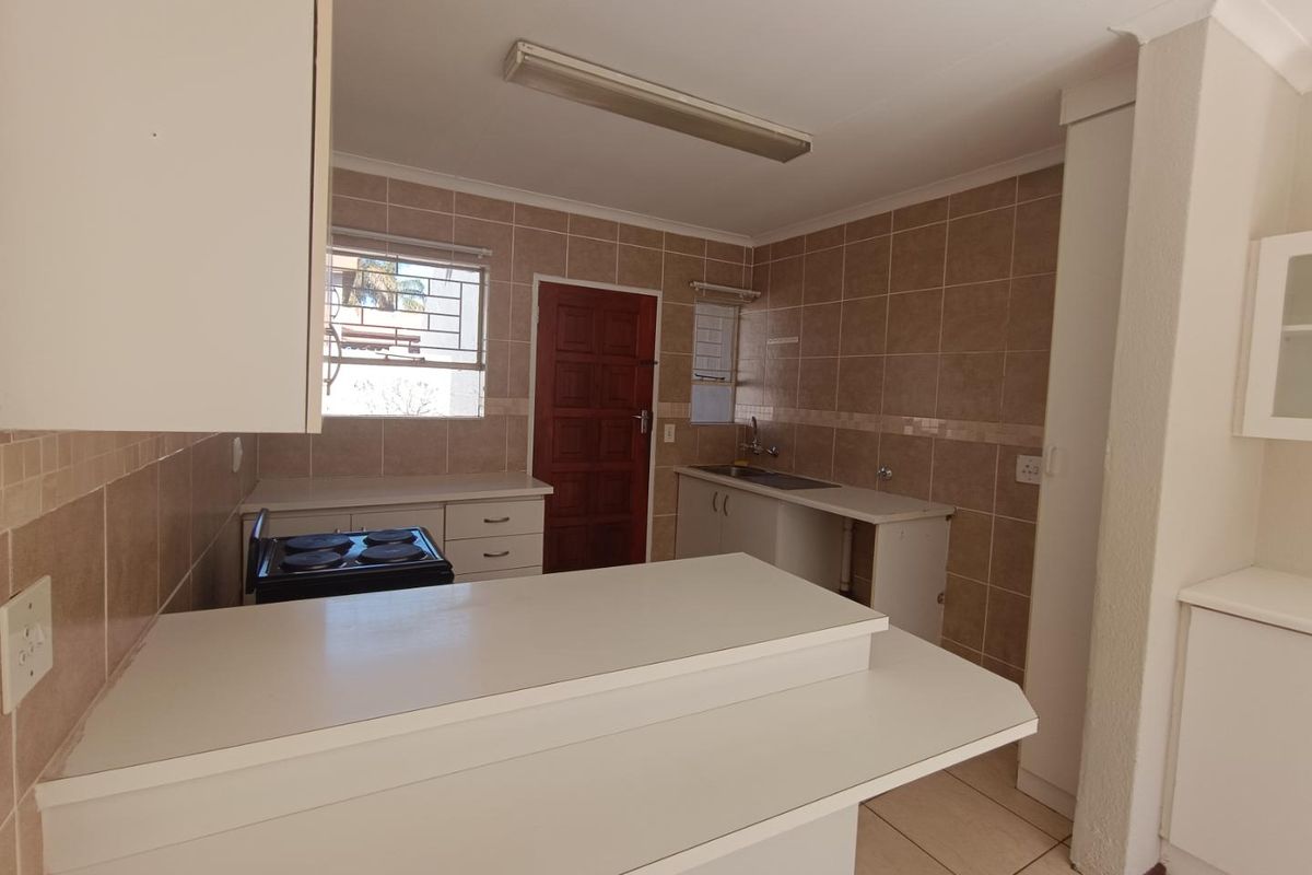 A functional kitchen featuring tiled walls, built-in cabinetry, a breakfast bar, and a stainless steel sink, offering a clean, blank canvas for renovation.