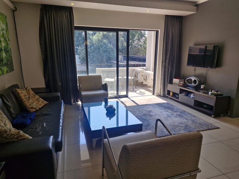 A spacious living room featuring tiled flooring, recessed ceiling lights, and large sliding glass doors that provide access to an outdoor balcony area.
