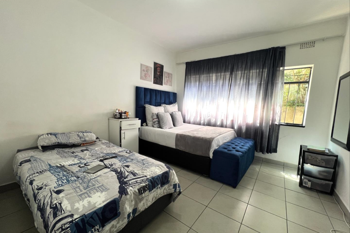 A functional bedroom featuring tiled flooring and a large window with curtain rails, providing natural light and a neutral base for interior design.