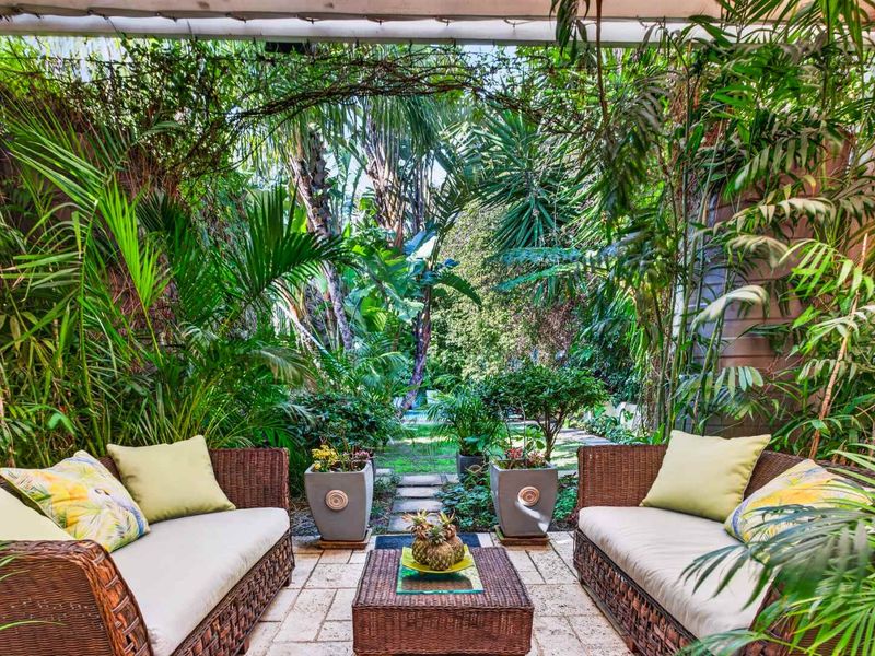A lush, private covered patio area featuring stone paving and dense garden landscaping, creating a tranquil outdoor retreat.
