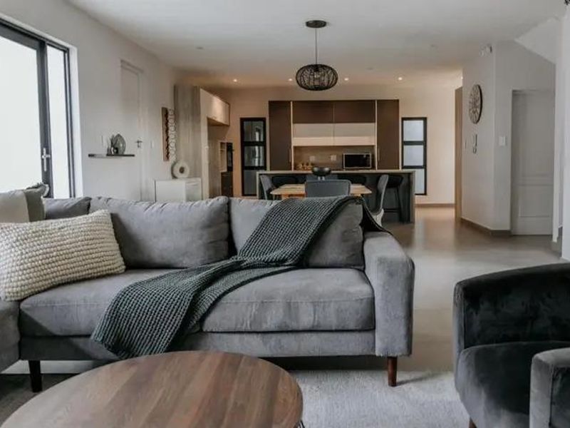 Modern open-plan living area featuring a contemporary kitchen with a central island, sleek cabinetry, and seamless flow to the lounge space.
