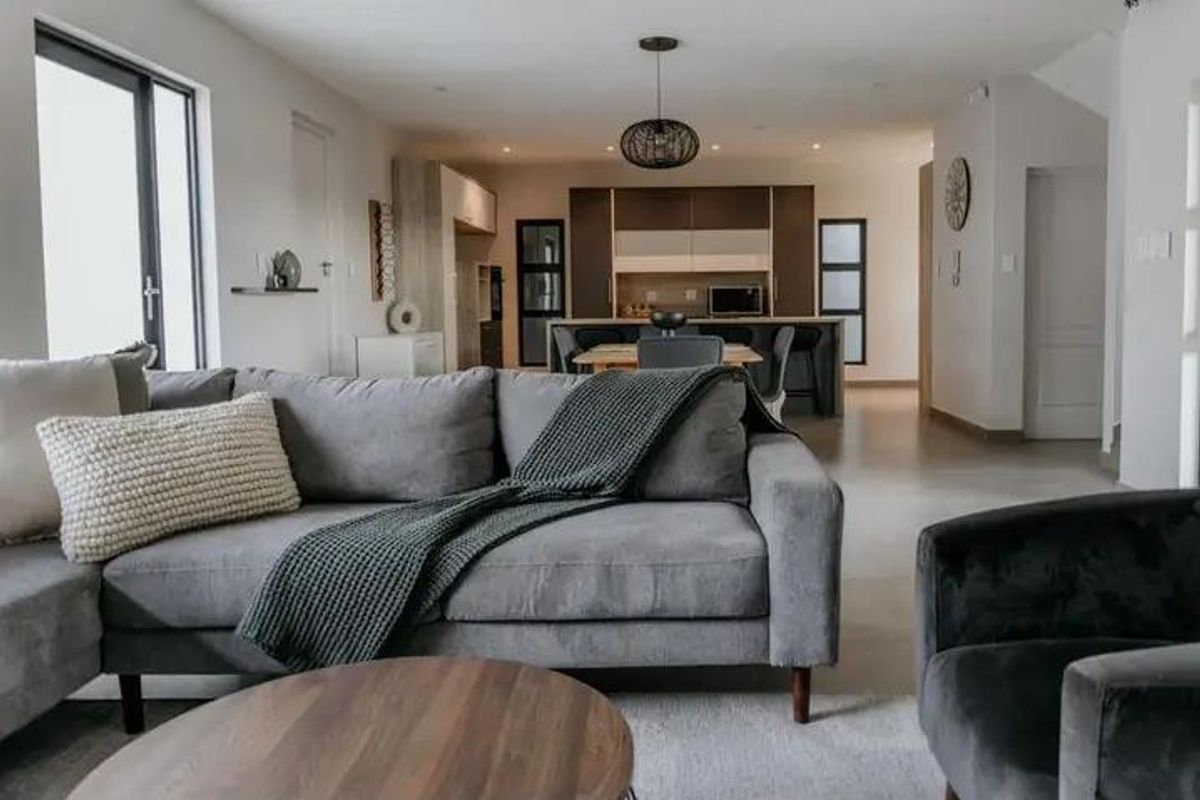 Modern open-plan living area featuring a contemporary kitchen with a central island, sleek cabinetry, and seamless flow to the lounge space.