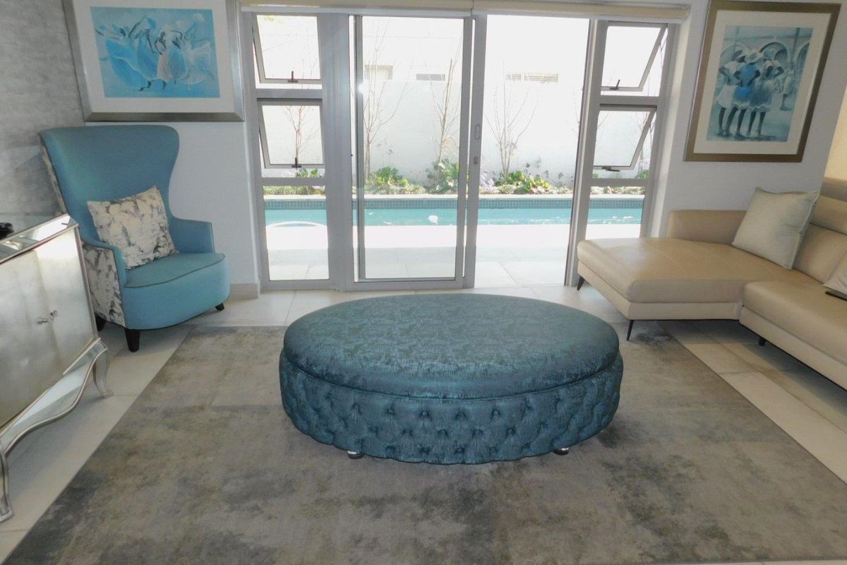 A bright living room featuring large sliding glass doors that open directly onto a private swimming pool area.