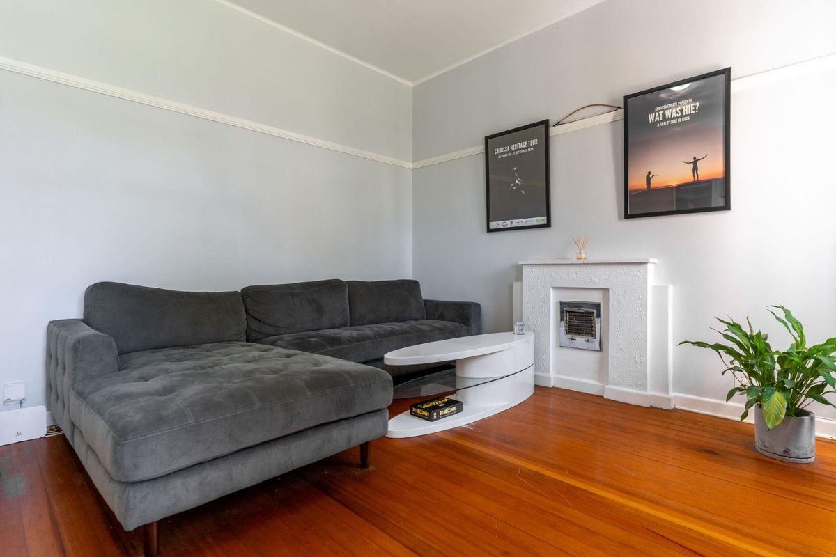 A living room featuring original polished timber flooring, picture rails, and a decorative built-in fireplace surround.