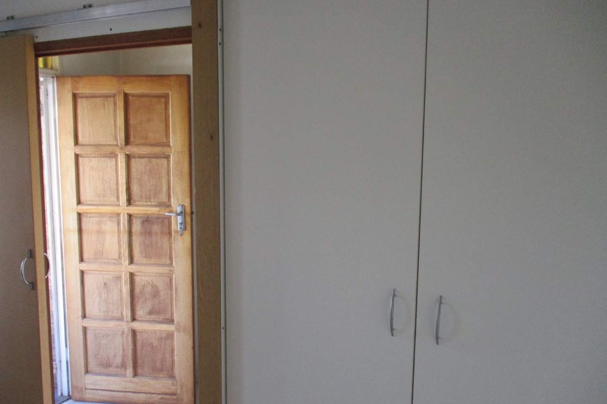 Interior view showing built-in white cabinetry and a wooden panelled door leading to an adjacent space.