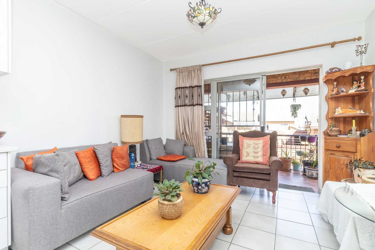 A living room featuring tiled flooring and a sliding glass door that opens onto a balcony, providing natural light and outdoor access.