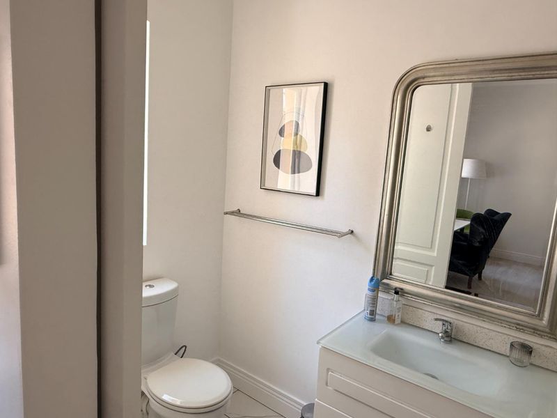 A functional bathroom featuring a vanity cabinet with an integrated sink, a wall-mounted mirror, and a standard toilet.