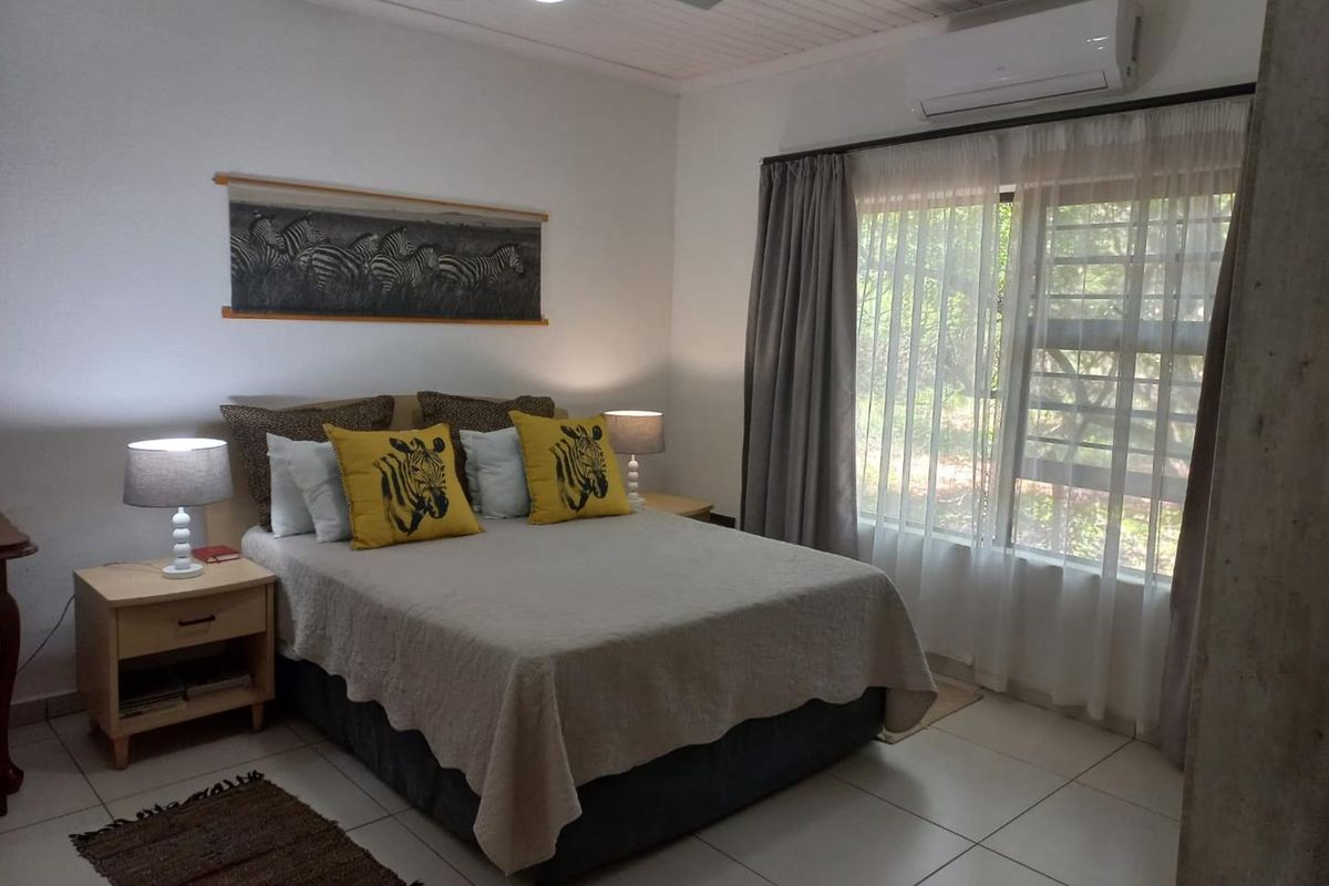 A well-maintained bedroom featuring tiled flooring, a ceiling fan, and a wall-mounted air conditioning unit.