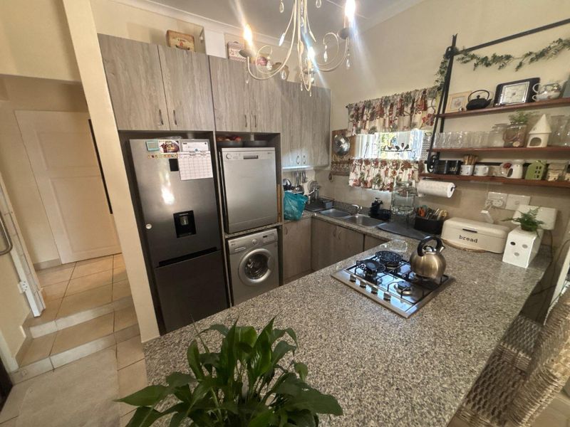 Compact kitchen featuring granite countertops, a gas hob, built-in cabinetry, and tiled flooring, providing a functional workspace.
