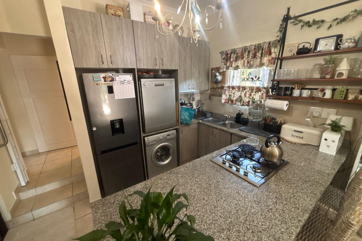 Compact kitchen featuring granite countertops, a gas hob, built-in cabinetry, and tiled flooring, providing a functional workspace.