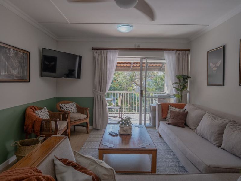 A comfortable living room featuring laminate flooring, a ceiling fan, and direct access to a private balcony through sliding glass doors.