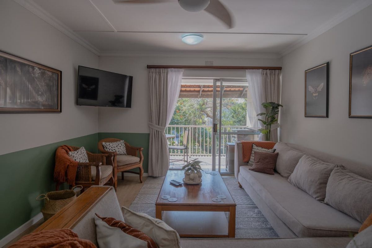 A comfortable living room featuring laminate flooring, a ceiling fan, and direct access to a private balcony through sliding glass doors.