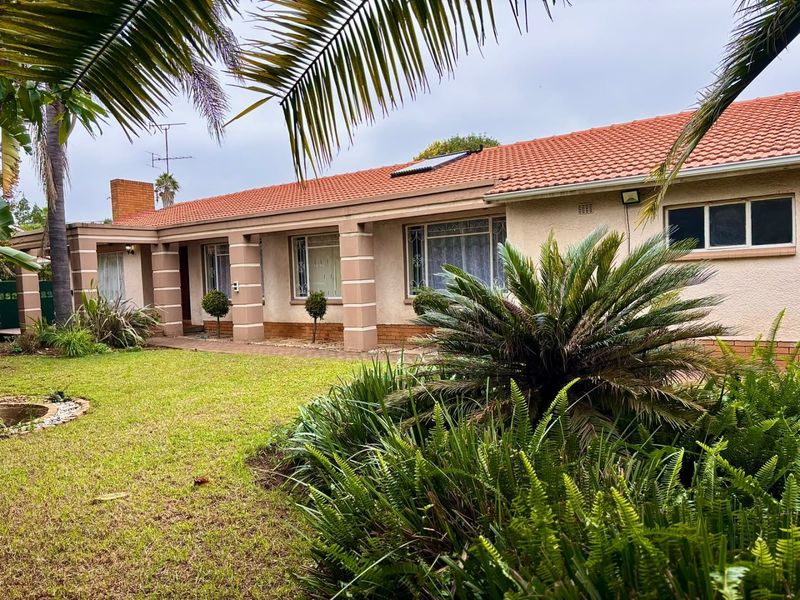 Front elevation of a single-story house featuring a terracotta tiled roof, covered porch with columns, and a well-maintained front garden.